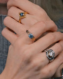 Close-up of a hand wearing multiple celtic rings with gemstones on a blurred background